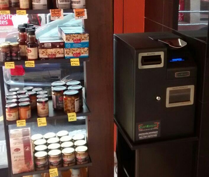 CashKeeper en un comerç de productes alimentaris al costat de prestatgeries